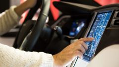 Eine Person, die in einem Auto sitzt und das Navi über das Touch-Display bedient.