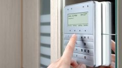 Eine Person bedient ein Sicherheitssystem-Panel neben einer Tür. 