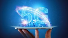 Männliche Hand hält ein Smartphone mit einem 5G-Hologramm auf dem Hintergrund einer Stadt. 